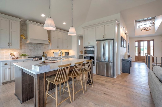 kitchen with appliances with stainless steel finishes, custom exhaust hood, light countertops, and a sink