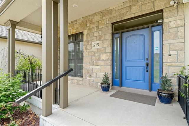 entrance to property featuring a porch and stone siding