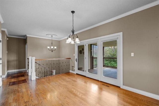 unfurnished dining area with visible vents, ornamental molding, wood finished floors, baseboards, and a chandelier