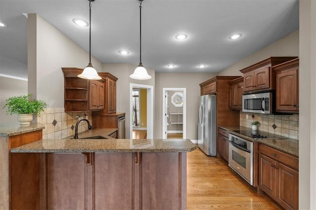 kitchen featuring open shelves, a peninsula, light stone counters, a sink, and appliances with stainless steel finishes