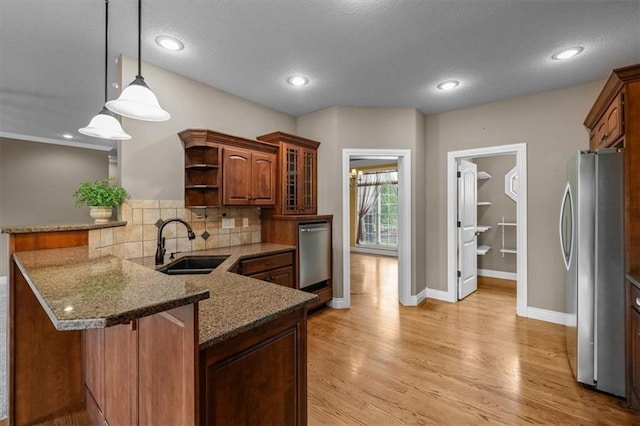 kitchen featuring open shelves, light wood-type flooring, tasteful backsplash, a sink, and stainless steel appliances