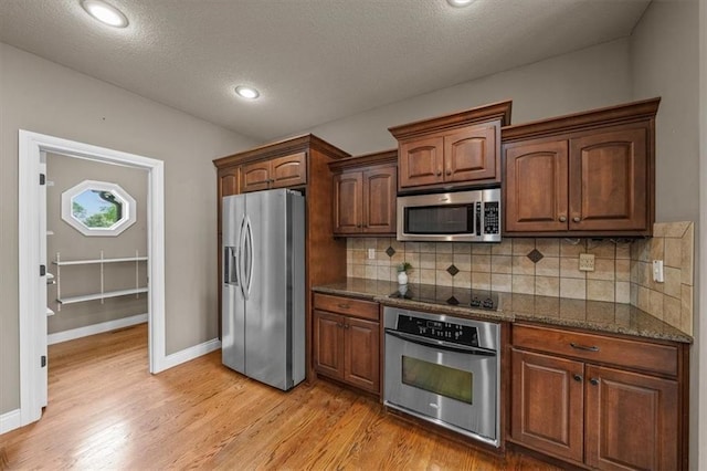 kitchen featuring baseboards, appliances with stainless steel finishes, decorative backsplash, and light wood-style floors