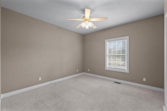 empty room featuring carpet flooring, a textured ceiling, a ceiling fan, baseboards, and visible vents
