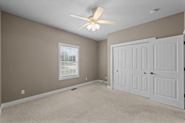 unfurnished bedroom featuring visible vents, a closet, baseboards, a textured ceiling, and carpet