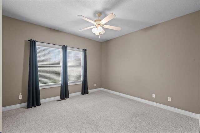 carpeted spare room featuring a textured ceiling, ceiling fan, visible vents, and baseboards