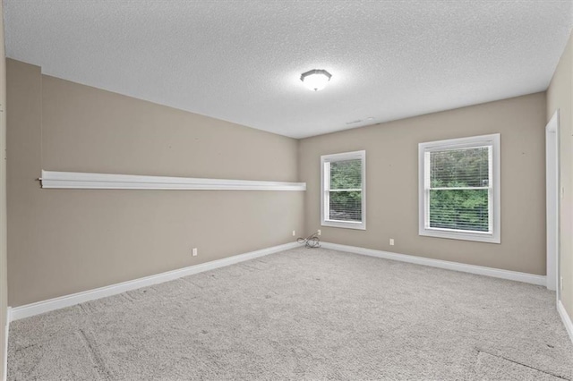 carpeted spare room featuring baseboards and a textured ceiling