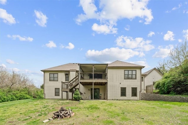back of property with a wooden deck, a sunroom, a lawn, an outdoor fire pit, and stairway