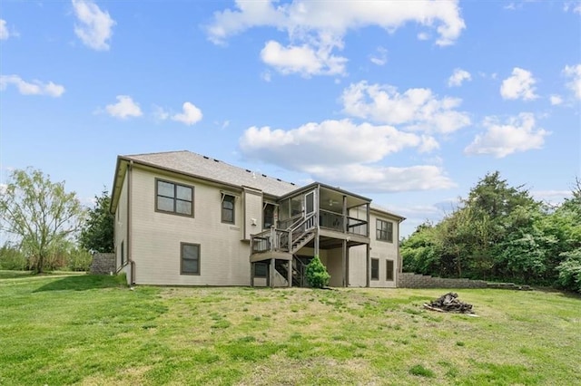 back of property with a deck, a sunroom, a lawn, an outdoor fire pit, and stairway