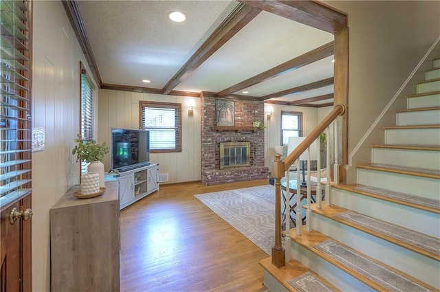 10312 Lamar Ave, Overland Park, KS 66207 - living area with a brick fireplace, wood finished floors, stairway, healthy amount of natural light, and crown molding