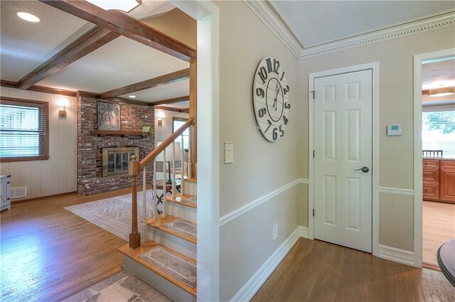 10312 Lamar Ave, Overland Park, KS 66207 - foyer featuring wood finished floors, a brick fireplace, stairway, beam ceiling, and baseboards