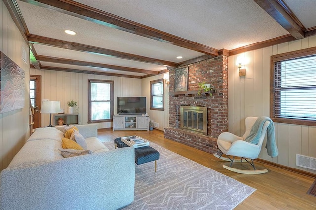 10312 Lamar Ave, Overland Park, KS 66207 - living area with a fireplace, beam ceiling, wood finished floors, a textured ceiling, and a decorative wall