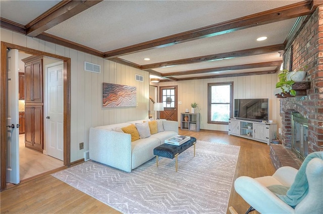 10312 Lamar Ave, Overland Park, KS 66207 - living area featuring beam ceiling, light wood finished floors, a brick fireplace, and a textured ceiling
