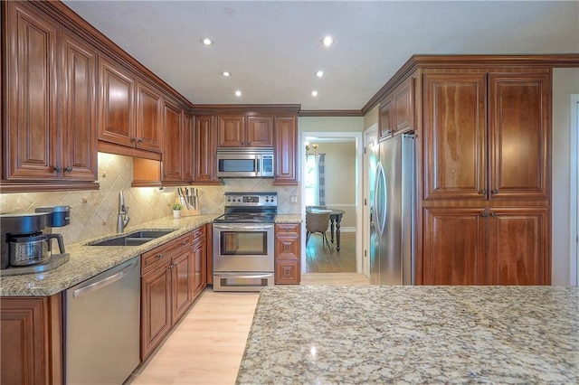 10312 Lamar Ave, Overland Park, KS 66207 - kitchen featuring appliances with stainless steel finishes, a sink, light wood-style flooring, light stone counters, and recessed lighting