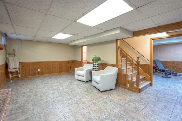 10312 Lamar Ave, Overland Park, KS 66207 - living area with a wainscoted wall, a drop ceiling, wooden walls, and stairs