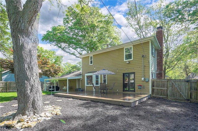 10312 Lamar Ave, Overland Park, KS 66207 - back of property with a deck, fence, a chimney, and a gate