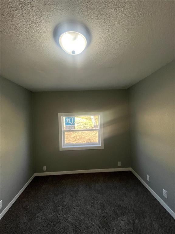 unfurnished room featuring baseboards, dark carpet, and a textured ceiling