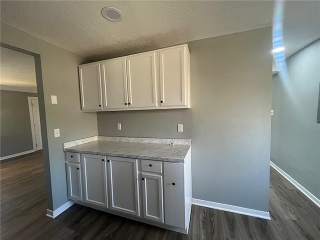 kitchen featuring dark wood finished floors, baseboards, and white cabinets