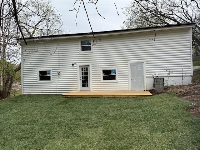 rear view of house featuring central air condition unit and a yard