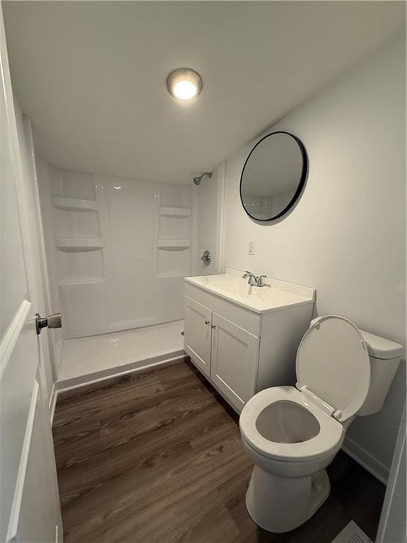 full bath featuring vanity, toilet, baseboards, walk in shower, and wood finished floors