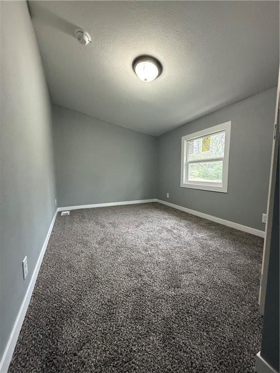 carpeted spare room with baseboards and a textured ceiling