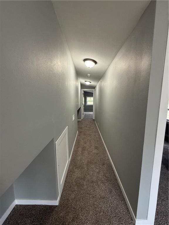 corridor featuring baseboards and carpet flooring