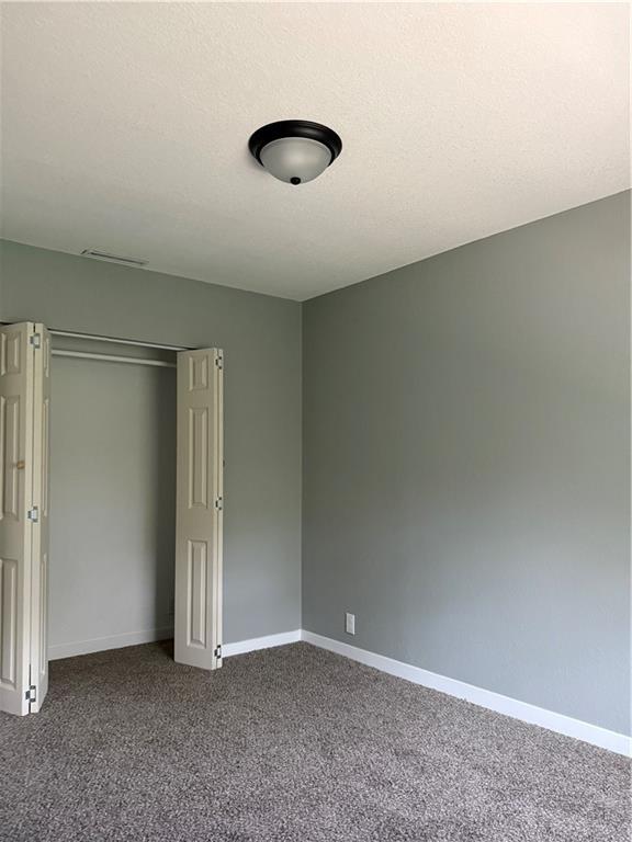 unfurnished bedroom with baseboards, a closet, dark carpet, and a textured ceiling