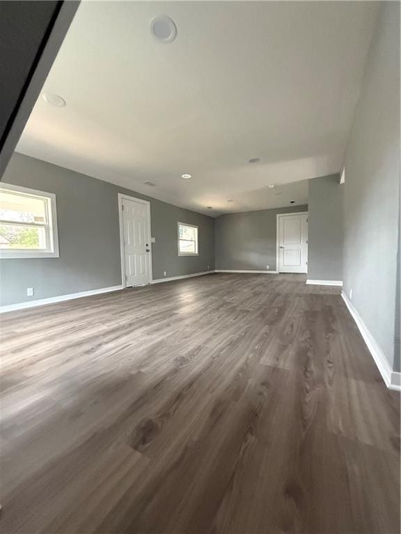 unfurnished living room featuring baseboards and dark wood-style floors