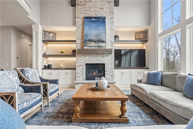 living area with a stone fireplace and a high ceiling