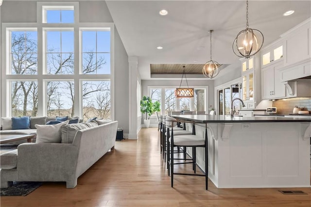 kitchen with dark countertops, a kitchen breakfast bar, a chandelier, white cabinetry, and recessed lighting