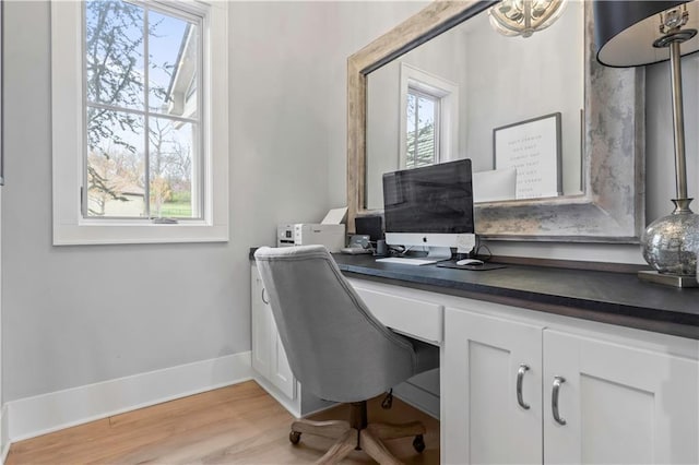 office space featuring plenty of natural light, baseboards, light wood-type flooring, and built in study area