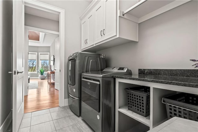 washroom with washer and clothes dryer, cabinet space, and light tile patterned floors