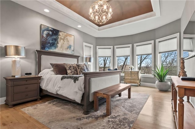 bedroom featuring a raised ceiling, light wood-style floors, baseboards, a chandelier, and recessed lighting