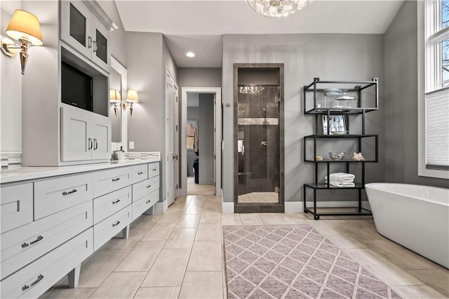 bathroom featuring a tile shower, recessed lighting, tile patterned flooring, vanity, and a freestanding tub