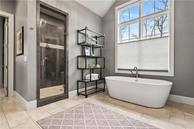 bathroom featuring a stall shower, lofted ceiling, a soaking tub, tile patterned floors, and baseboards