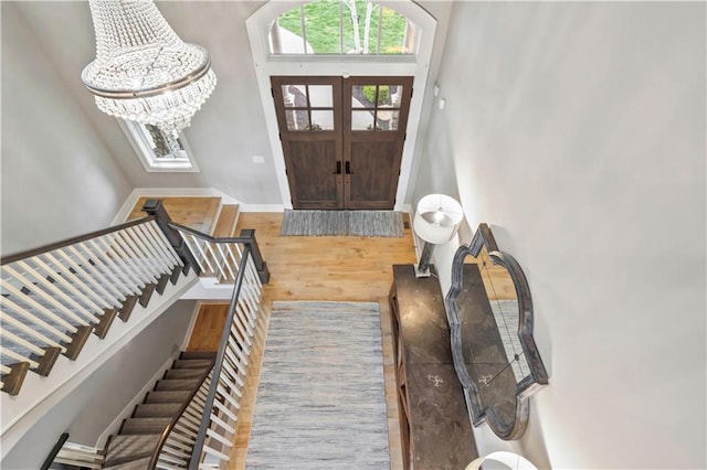 foyer featuring wood finished floors, a chandelier, stairway, and baseboards