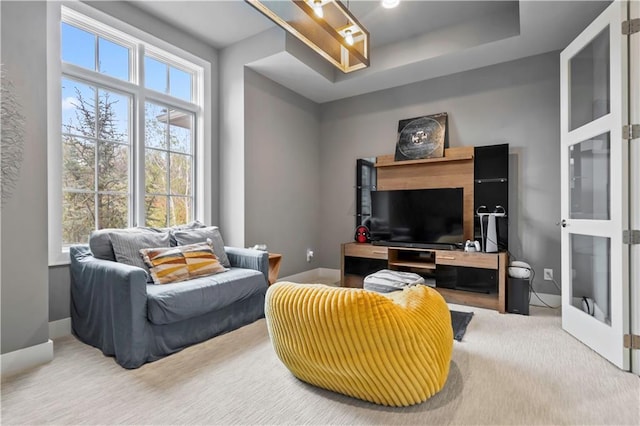 sitting room featuring a tray ceiling, french doors, and carpet