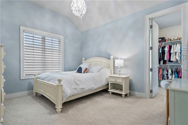 carpeted bedroom with a walk in closet, lofted ceiling, baseboards, a chandelier, and a closet