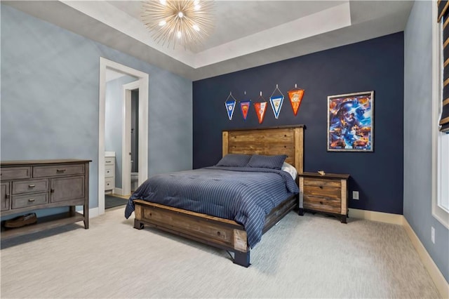 carpeted bedroom with baseboards, an accent wall, and a tray ceiling