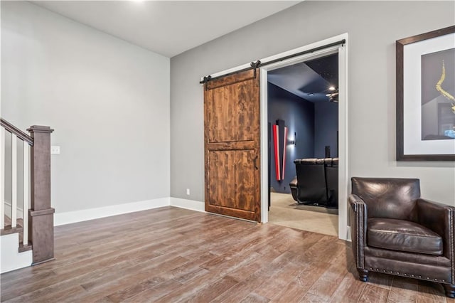 sitting room with stairs, wood finished floors, a barn door, and baseboards