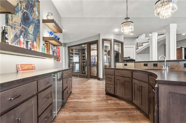 kitchen featuring a chandelier, dark countertops, a sink, dark brown cabinetry, and light wood-type flooring