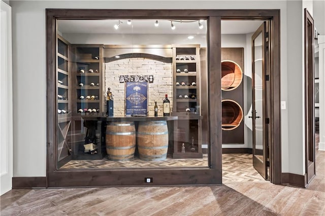 wine room featuring wood finished floors, baseboards, and a dry bar