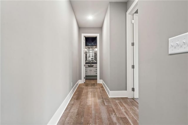 hall with wood finished floors, baseboards, and recessed lighting