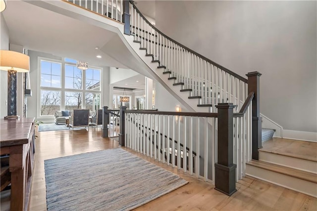stairway featuring a towering ceiling and wood finished floors