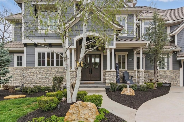 16401 W Loch Lloyd Pkwy, Loch Lloyd, MO 64012 - property entrance with stone siding, a balcony, a standing seam roof, and covered porch