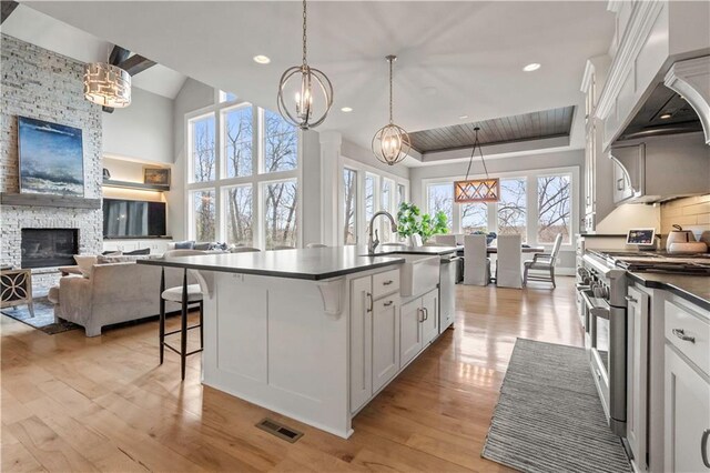 16401 W Loch Lloyd Pkwy, Loch Lloyd, MO 64012 - kitchen with appliances with stainless steel finishes, dark countertops, a sink, custom range hood, and light wood finished floors