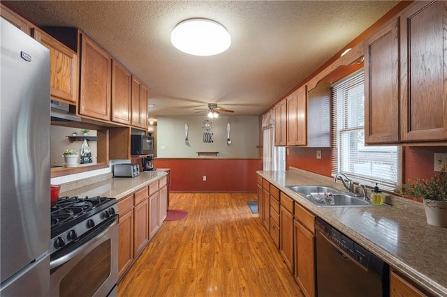 kitchen with ceiling fan, a sink, black appliances, under cabinet range hood, and light wood-style flooring