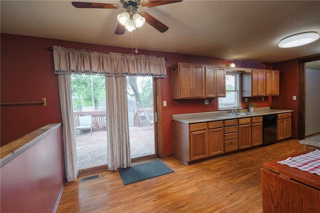 kitchen with visible vents, light wood-style floors, ceiling fan, a sink, and dishwasher