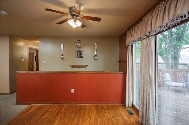 unfurnished dining area with a ceiling fan, baseboards, visible vents, and wood finished floors
