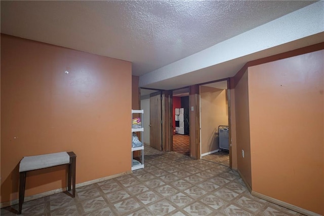 finished basement featuring baseboards, a textured ceiling, and light floors