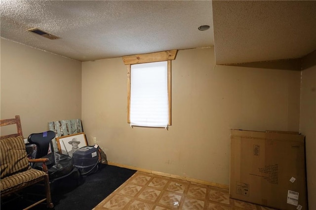 living area featuring baseboards, a textured ceiling, and visible vents